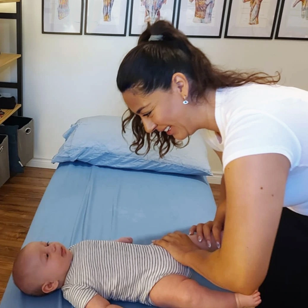 Ana Sierra, ostéopathe pédiatrique à Blainville, souriant à un bébé durant une séance de soin doux et rassurant.