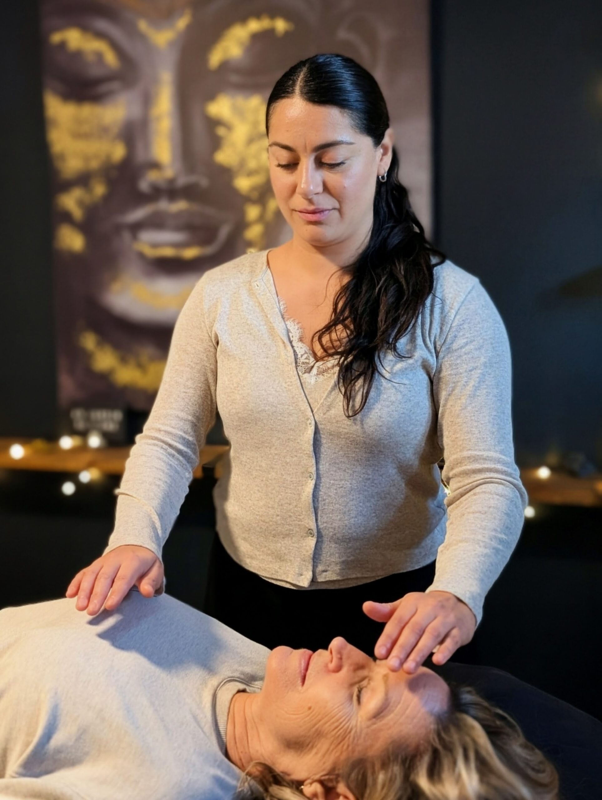 Ana Sierra, praticienne Reiki chez Mouvement Essĕre à Blainville, effectuant un soin énergétique par imposition des mains sur une cliente détendue.